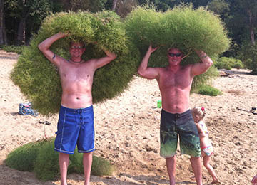 two guys holding seaweed over their heads width=